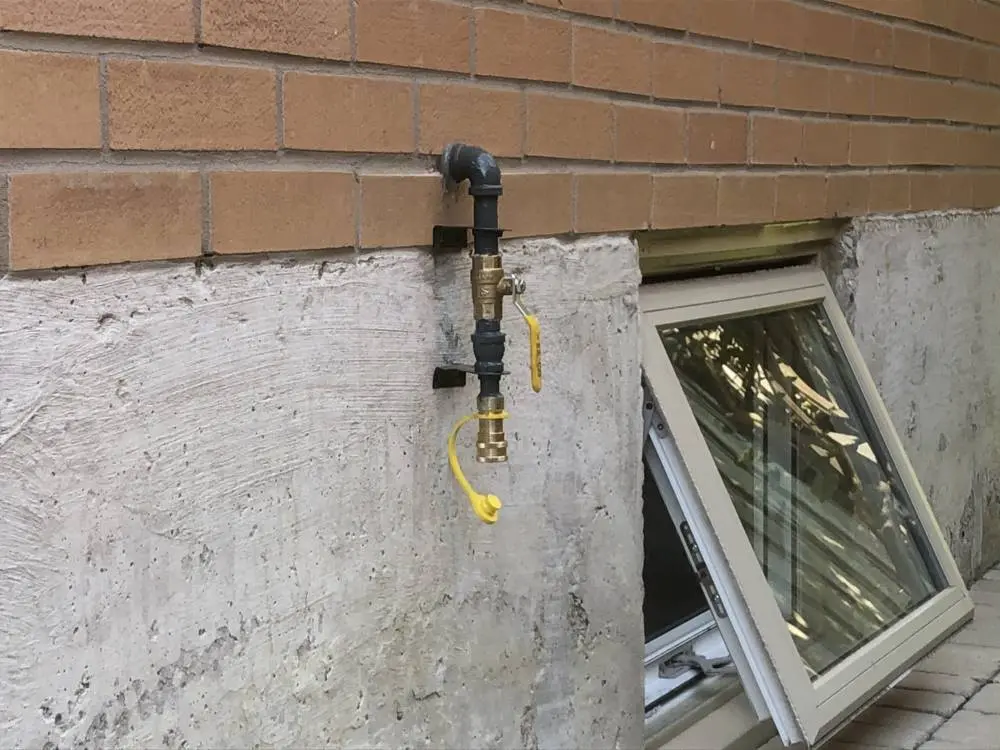 Exterior natural gas shutoff valve installed on a residential home wall, providing safe gas control for furnace or HVAC system connection