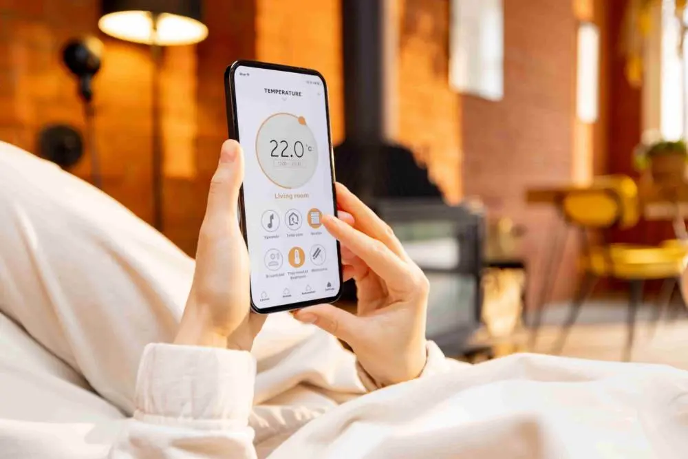 A person using a smartphone app to control indoor temperature settings remotely