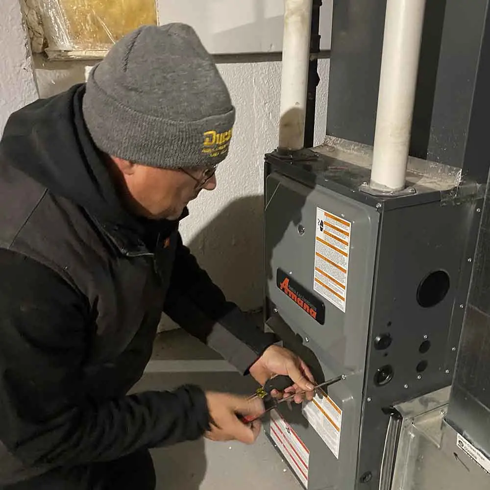 Professional HVAC technician repairing an Amana furnace for efficient home heating