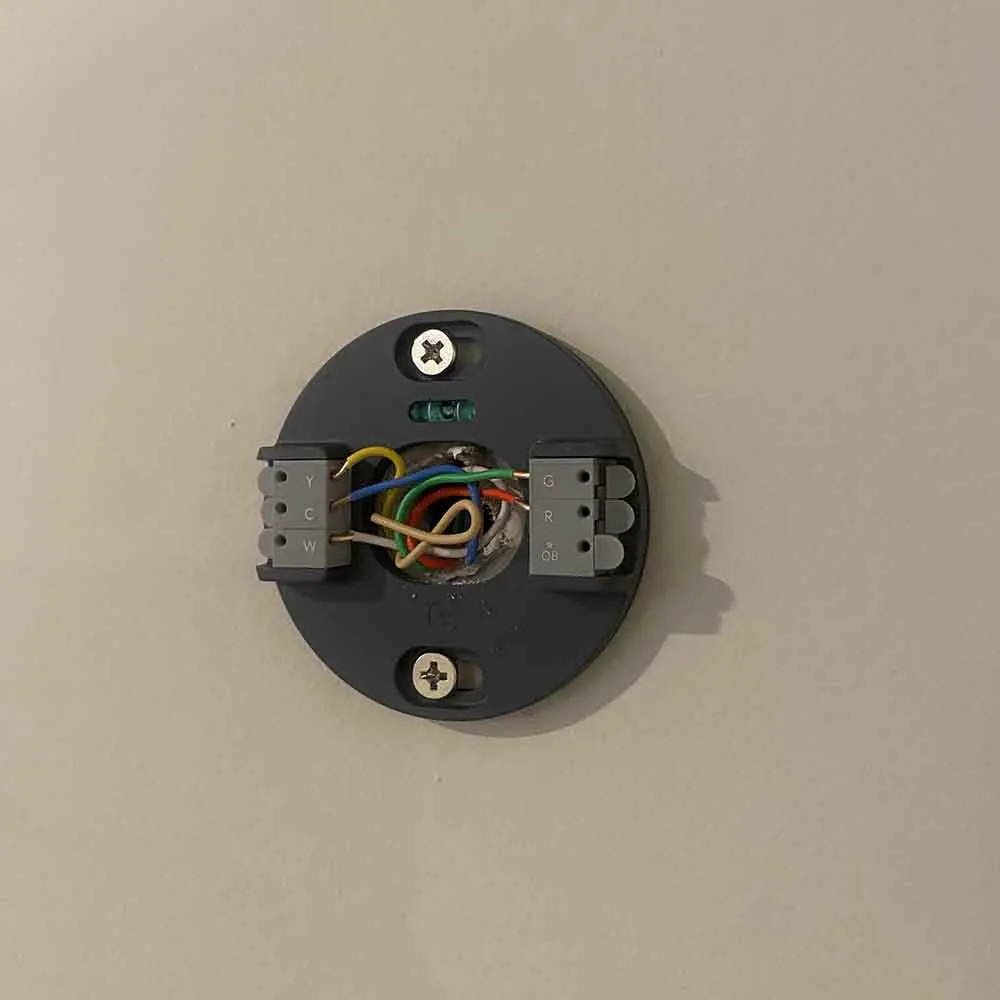 A mounted thermostat wiring base with multiple coloured wires exposed, ready for a smart thermostat installation