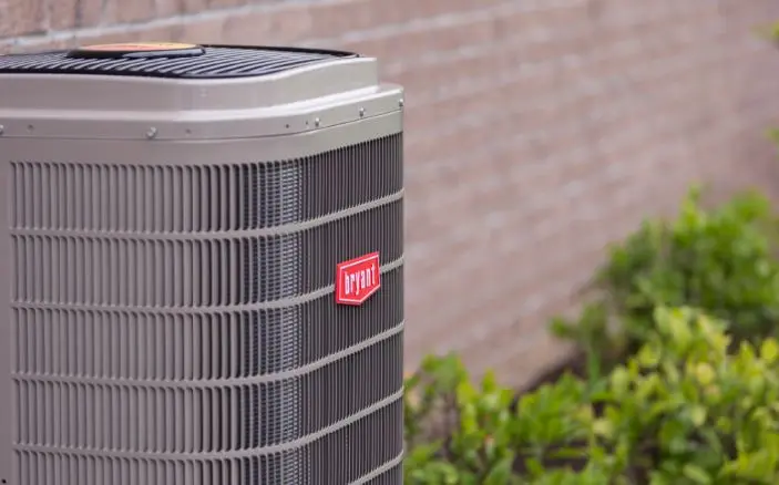 Close-up of a Bryant Evolution series central air conditioner condenser beside a brick wall in Mississauga