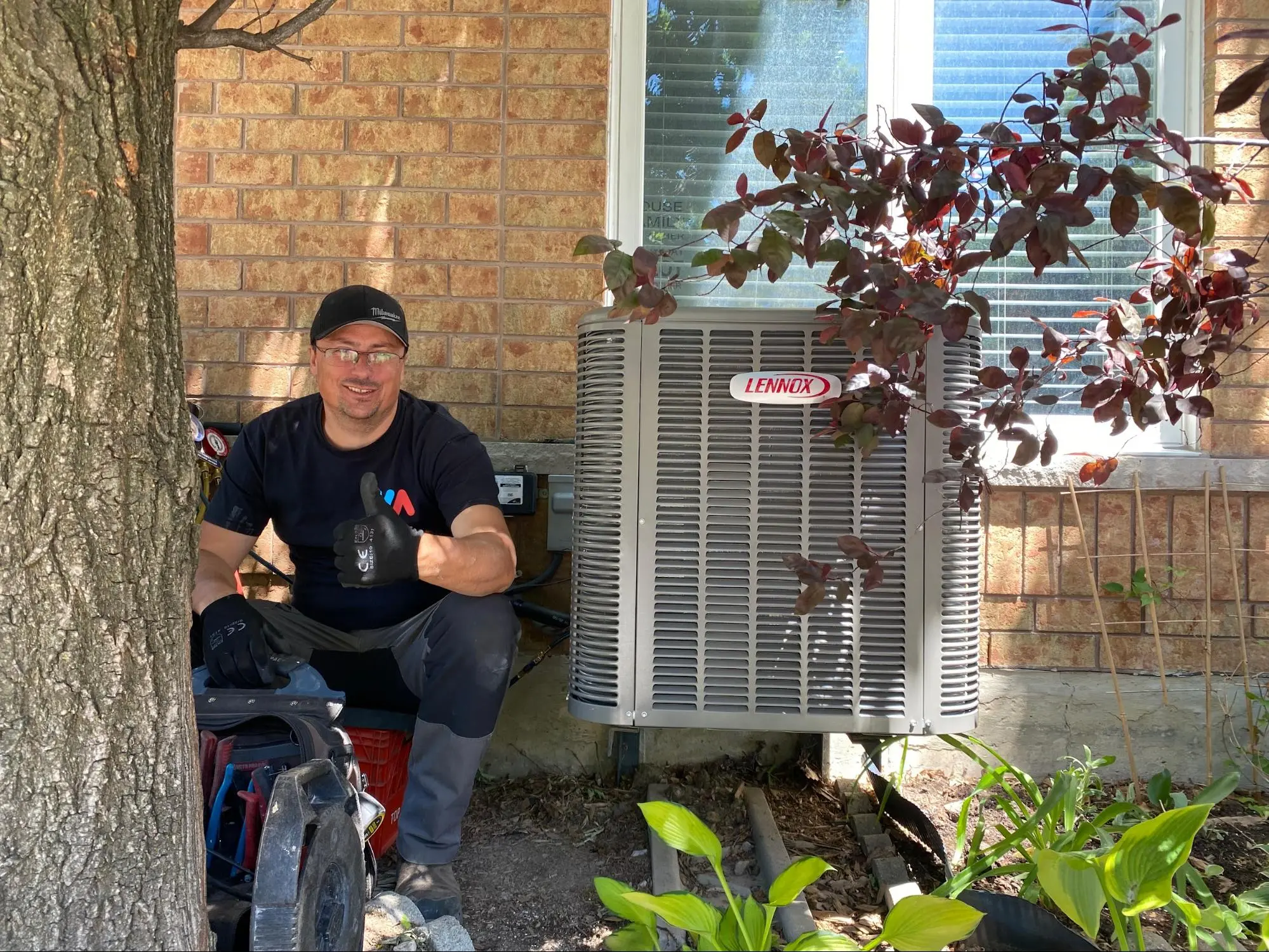 HVAC technician giving thumbs up beside newly installed Lennox air conditioner in Mississauga backyard