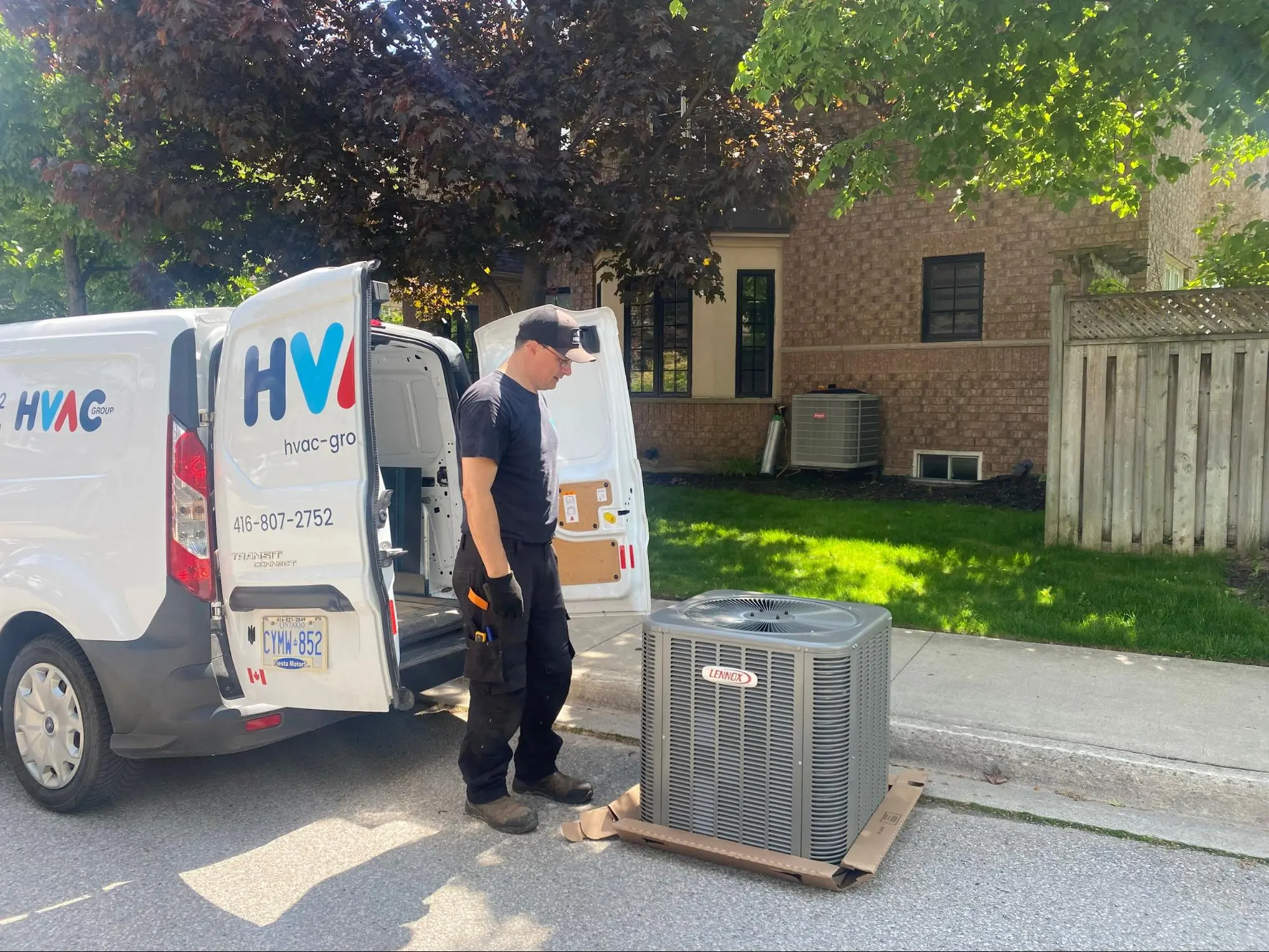 HVAC technician unloading Lennox air conditioner unit from service van in Mississauga