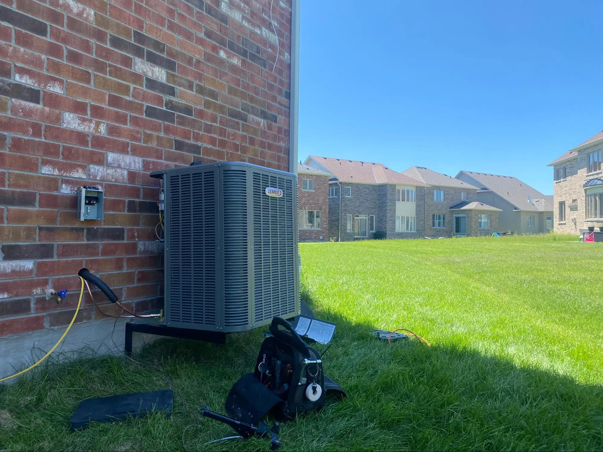 Lennox air conditioner installation beside brick house in Mississauga residential backyard